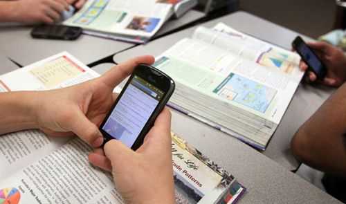 smartphone en las manos de un estudiante en su pupitre