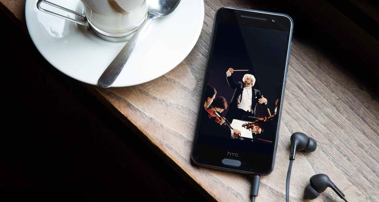 HTC One A9 con auriculares conectados y taza de café
