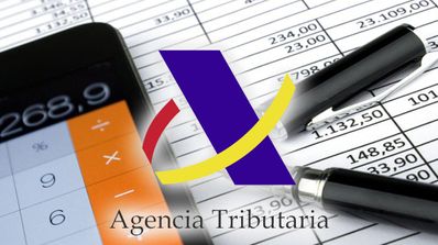 Móvil y bolígrafo con tablas y logo de la agencia tributaria