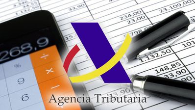 Móvil y bolígrafo con tablas y logo de la agencia tributaria