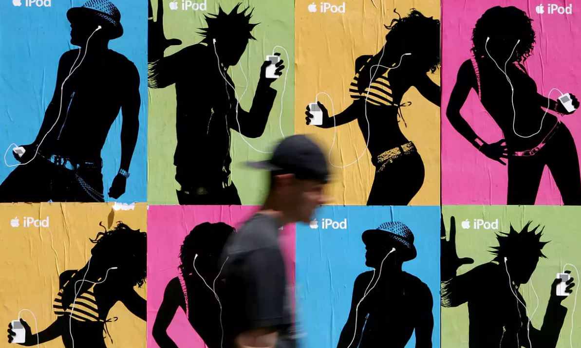 persona cruzando delante de carteles de publicidad de Apple