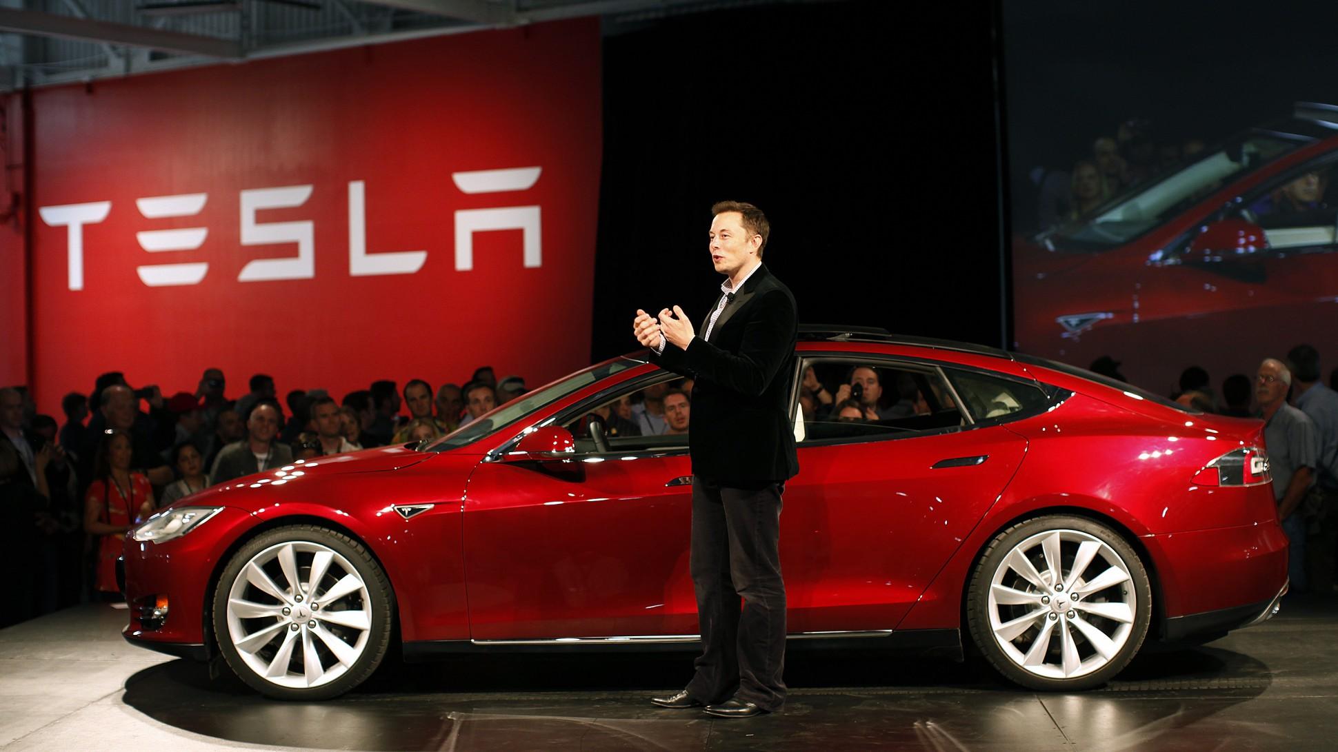 Elon Musk à côté d'une voiture Tesla
