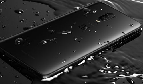 OnePlus 6 con carcasa de cristal sobre una superficie mojada