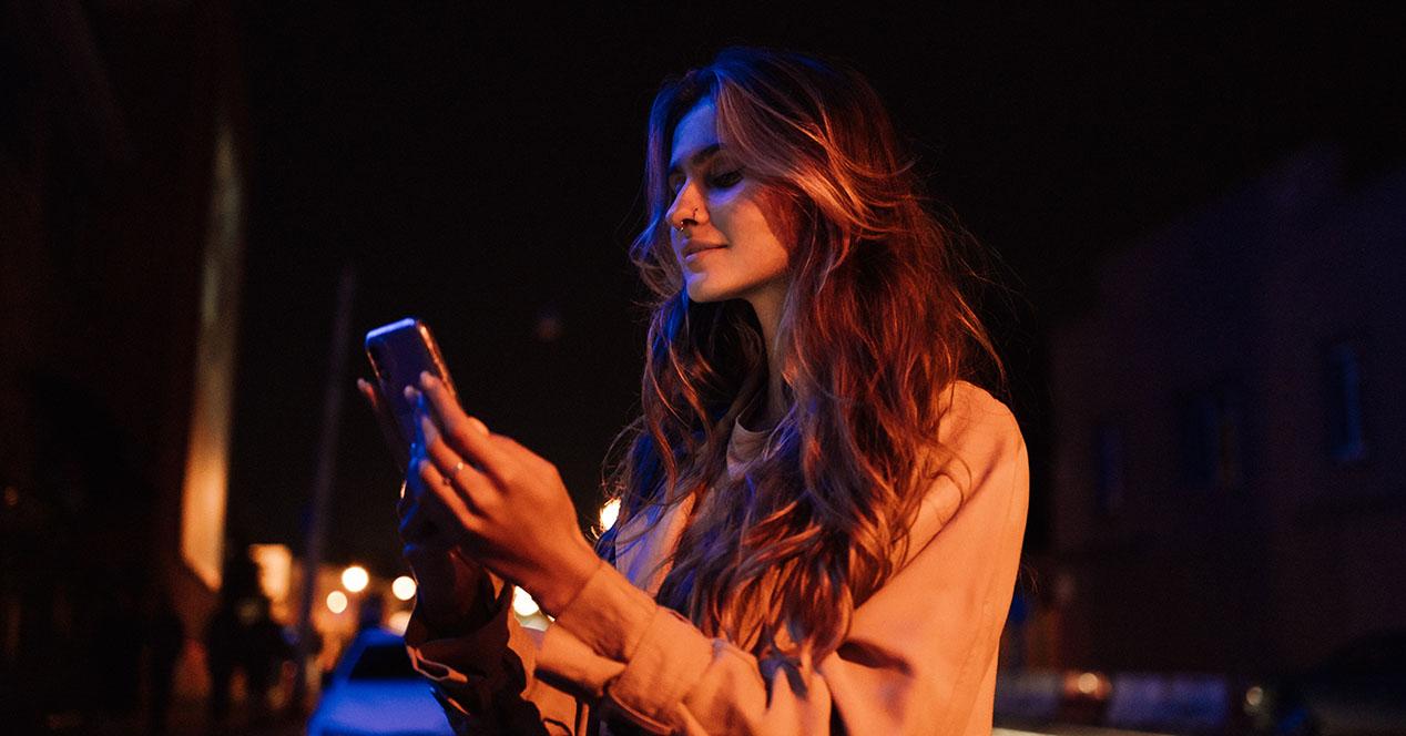 Chica usando el móvil de noche