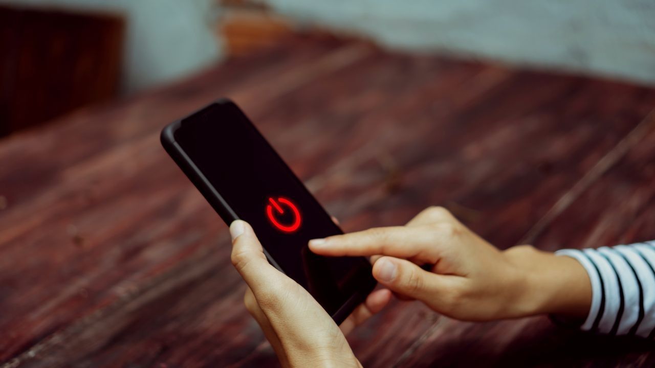 Dedo pulsando el icono rojo de encendido en la pantalla de un móvil