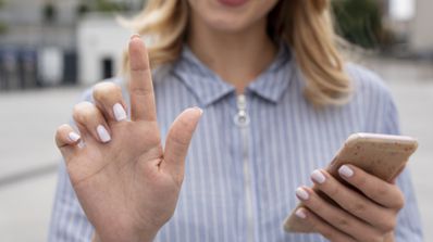 Mujer haciendo gestos con el móvil en la mano.