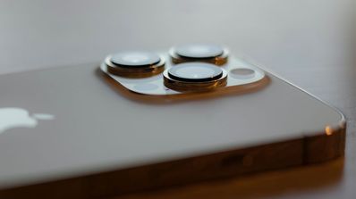 'Primer plano del módulo de tres cámaras de un iPhone Pro, destacando las lentes y el sensor LiDAR sobre un fondo oscuro.