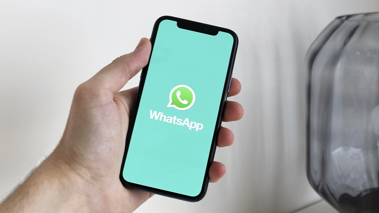 un usuario sostiene un iPhone con la app de WhatsApp abierta
