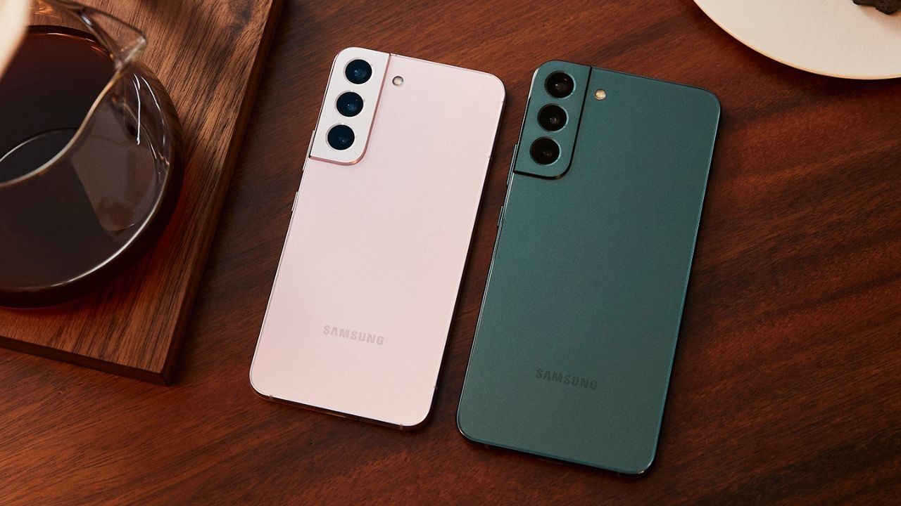 Parte trasera de los smartphones Samsung Galaxy S22 y S22 Plus en colores rosa y verde sobre una mesa de madera.