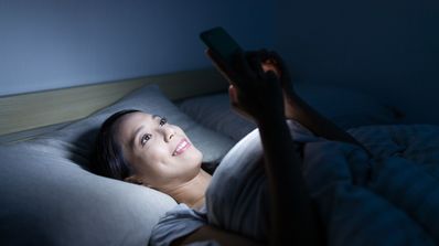 móvil en cama pantalla brilla