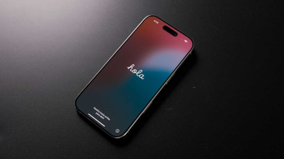 iPhone sobre fondo negro mostrando el mensaje de bienvenida Hola en pantalla tras una actualización de iOS.