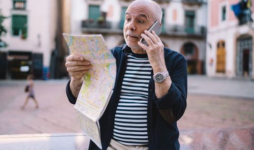 hombre haciendo llamada con mapa en mano