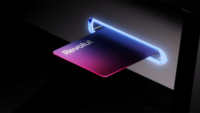 Tarjeta física de Revolut introducida en la ranura iluminada de un cajero automático.