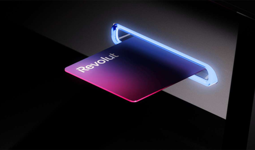 Tarjeta física de Revolut introducida en la ranura iluminada de un cajero automático.