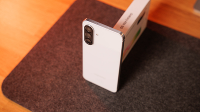 Parte trasera de un smartphone Samsung Galaxy A56 blanco con triple cámara en vertical sobre una alfombrilla oscura.