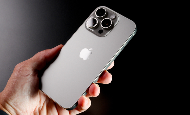 Parte trasera de un iPhone 16 Pro en color titanio natural sostenido con una mano.