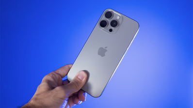iPhone 15 Pro en la mano sobre fondo azul.