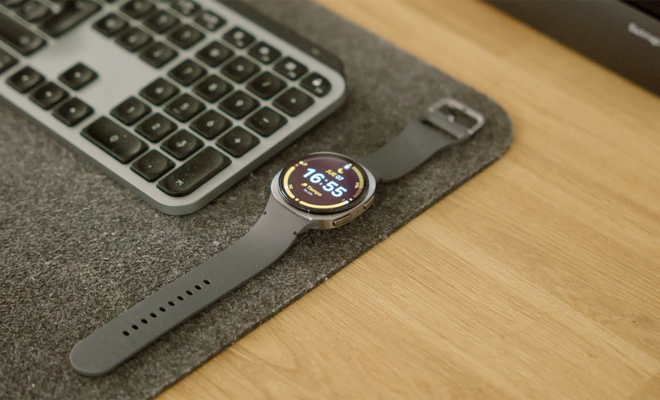 Reloj inteligente Samsung Galaxy Watch8 con esfera circular y correa oscura sobre un escritorio junto a un teclado inalámbrico.