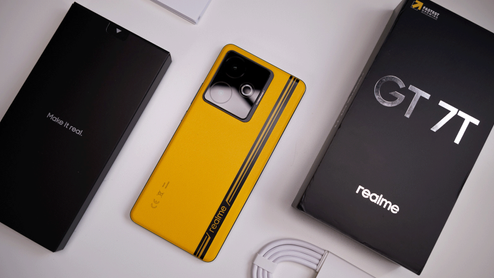 Parte trasera de un realme GT 7T de color amarillo con su caja original y cable de carga sobre un fondo blanco.