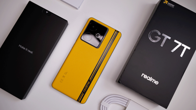 Parte trasera de un realme GT 7T de color amarillo con su caja original y cable de carga sobre un fondo blanco.