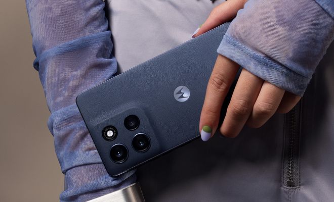 Primer plano de la mano de una persona sujetando un Motorola moto G86 5G de color azul oscuro, resaltando el módulo de cámaras trasero.