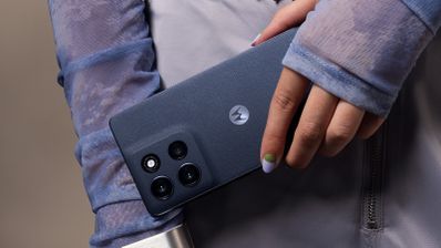 Primer plano de la mano de una persona sujetando un Motorola moto G86 5G de color azul oscuro, resaltando el módulo de cámaras trasero.