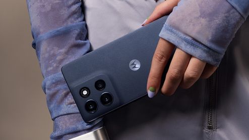 Primer plano de la mano de una persona sujetando un Motorola moto G86 5G de color azul oscuro, resaltando el módulo de cámaras trasero.