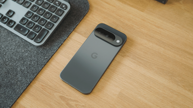 Parte trasera de un Google Pixel 10 en color oscuro sobre una mesa de madera junto a un teclado.