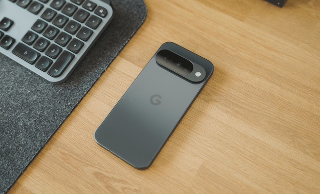 Parte trasera de un Google Pixel 10 en color oscuro sobre una mesa de madera junto a un teclado.