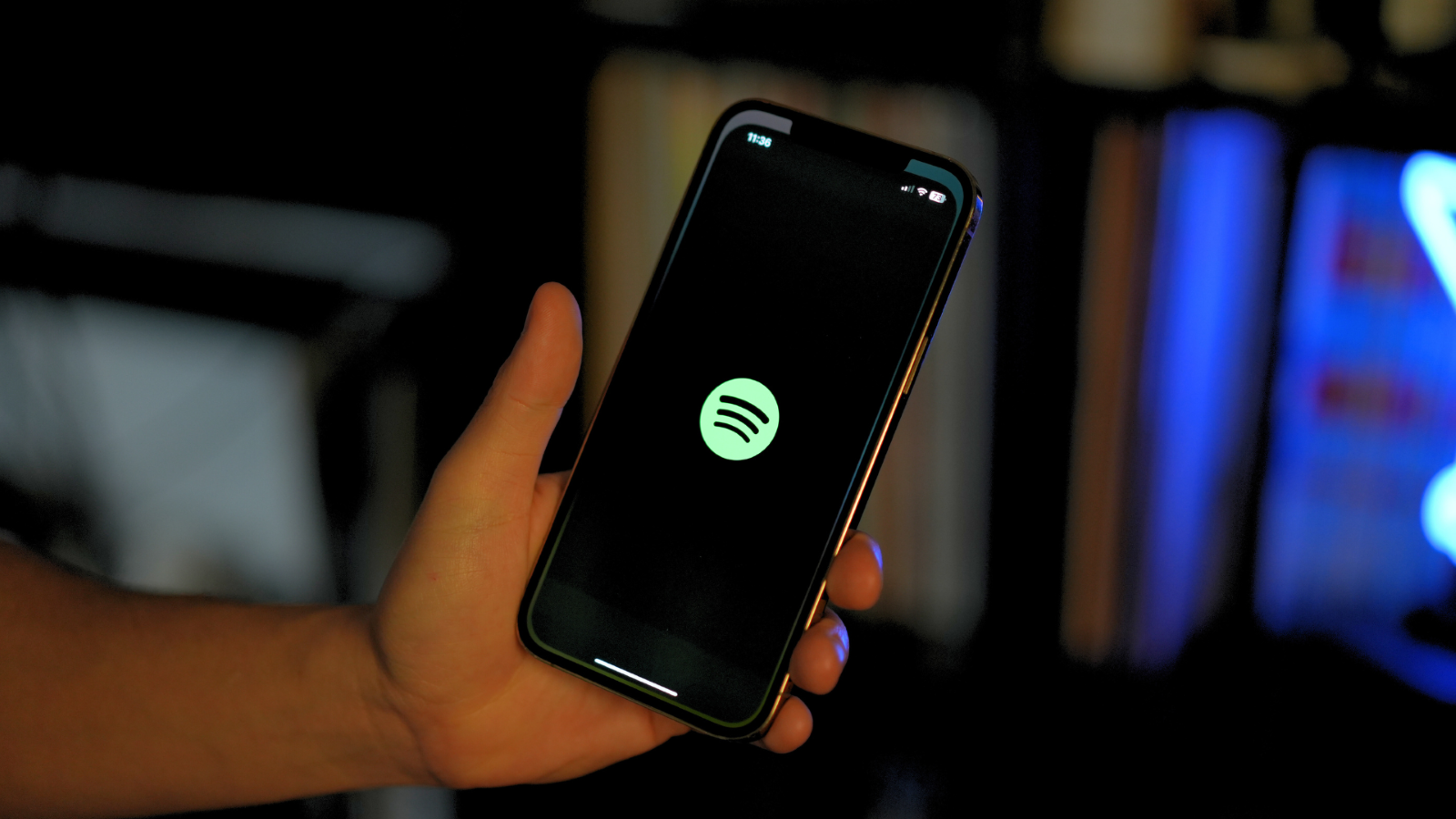 Mano sujetando un teléfono móvil con el logotipo verde de Spotify centrado en la pantalla negra.