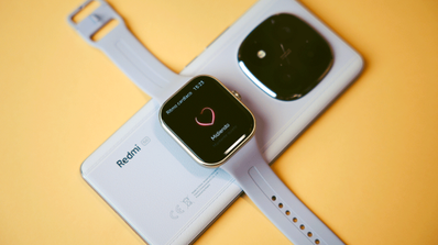 Reloj inteligente Redmi Watch 5 con correa azul claro mostrando la interfaz de medición de ritmo cardíaco sobre un teléfono móvil.