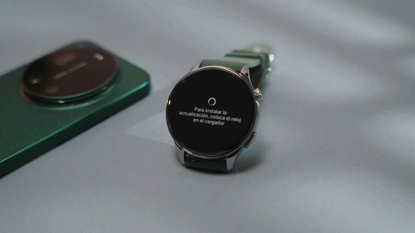 Reloj inteligente Xiaomi Watch 5 mostrando un aviso de actualización de software en pantalla junto a un teléfono móvil.