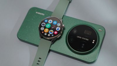 Reloj inteligente Xiaomi Watch 5 con pantalla circular apoyado sobre la parte trasera de un teléfono móvil con módulo de cámaras circular de Leica.