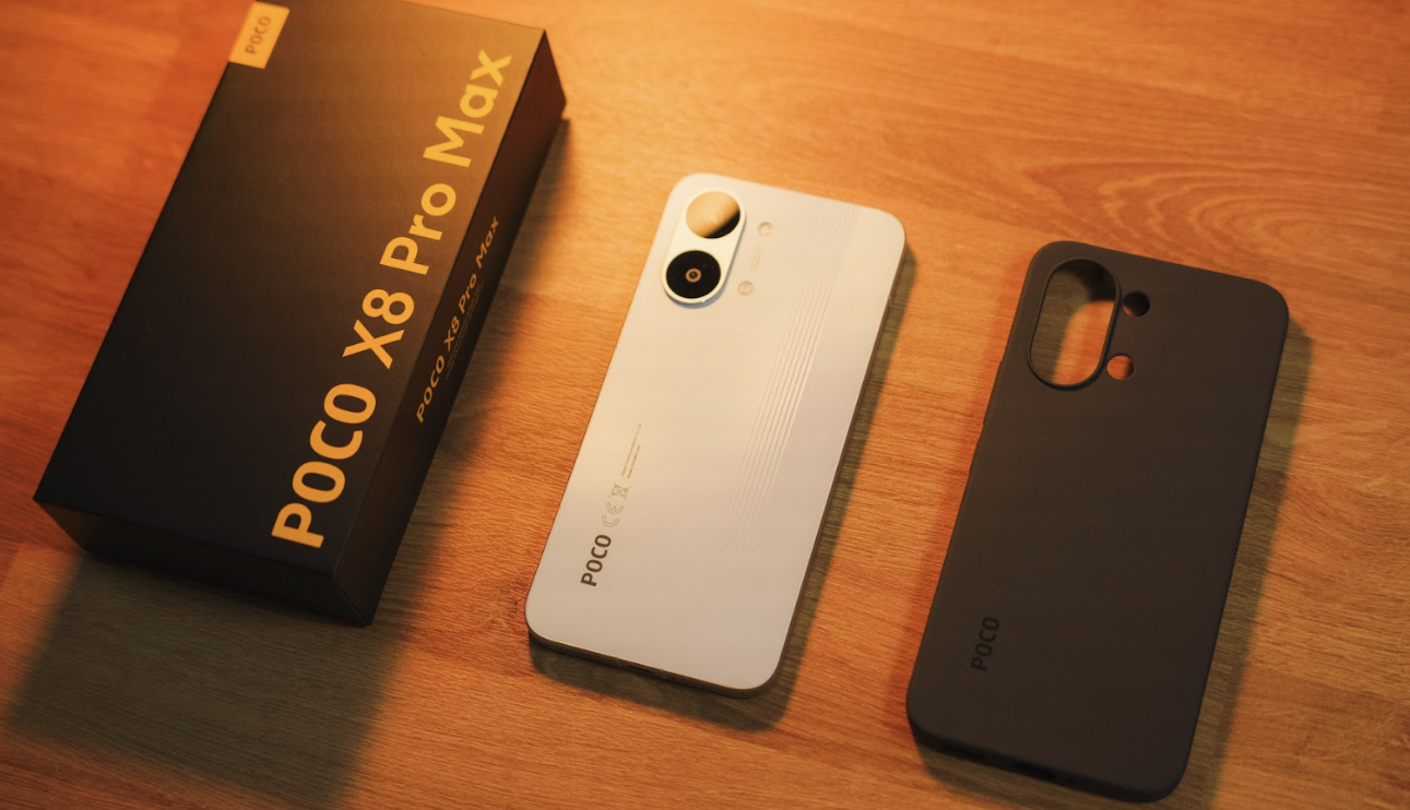Contenido de la caja del POCO X8 Pro Max con el teléfono en color blanco, una funda protectora oscura y el embalaje original sobre madera.