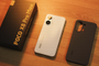 Contenido de la caja del POCO X8 Pro Max con el teléfono en color blanco, una funda protectora oscura y el embalaje original sobre madera.