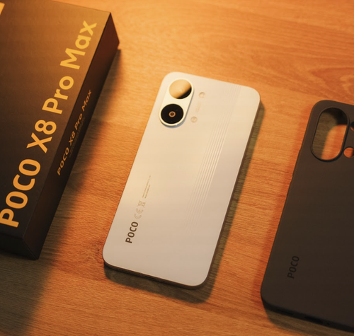 Parte trasera del teléfono POCO X8 Pro Max en color blanco junto a su caja y una funda protectora negra sobre una mesa de madera.