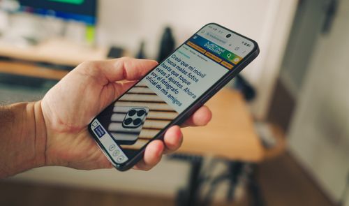 Mano sujetando un smartphone realme 16 5G mientras muestra un artículo en el navegador con el texto legible.