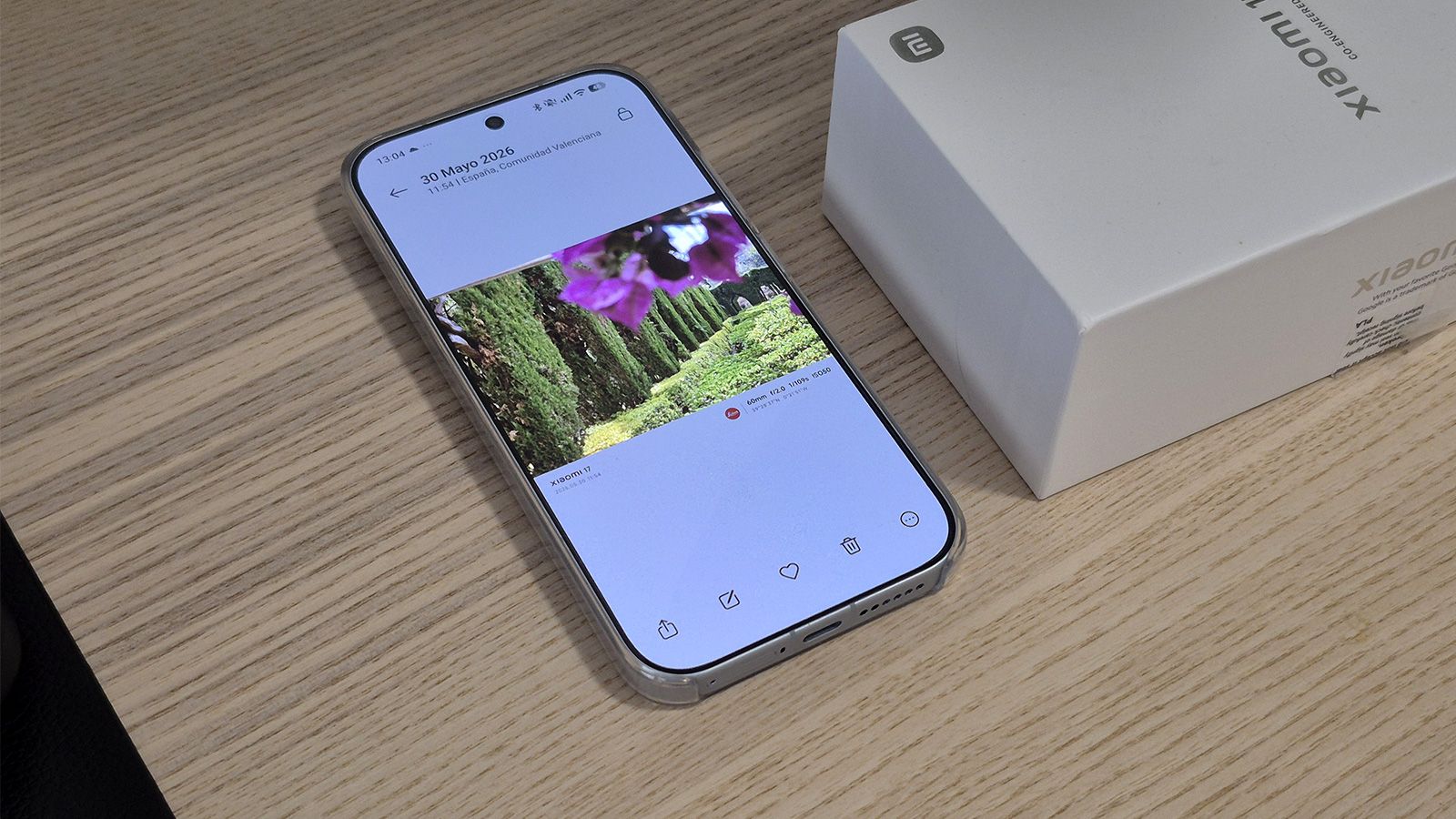 Interfaz de la galería y edición de fotos en un smartphone Xiaomi 17 sobre una mesa de madera junto a su caja.