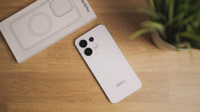 Parte trasera de un móvil OPPO blanco con tres cámaras circulares junto a su caja sobre una mesa de madera.