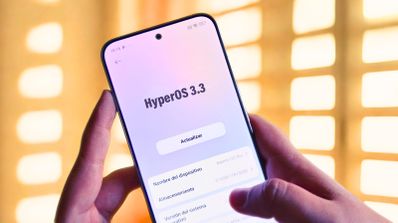 Smartphone sostenido con las manos mostrando la pantalla de actualización a HyperOS 3.3 con un botón central para actualizar.