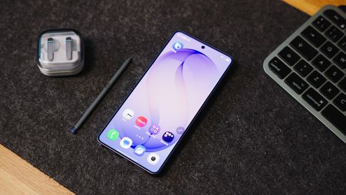 Frontal del Samsung Galaxy S26 Ultra encendido sobre un escritorio junto a su puntero óptico y unos auriculares.