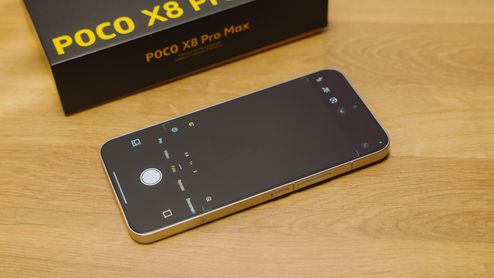 Interfaz de la aplicación de cámara abierta en un teléfono POCO X8 Pro Max junto a su caja original sobre una mesa de madera.