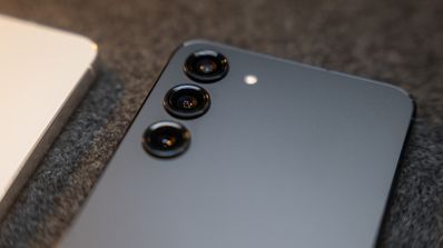 Primer plano de la parte trasera de un Samsung Galaxy S23+ de color oscuro donde se aprecian las tres lentes de la cámara alineadas verticalmente.