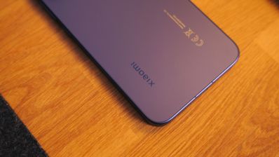 Detalle de la parte trasera inferior de un teléfono Xiaomi sobre una superficie de madera.