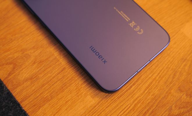 Detalle de la parte trasera inferior de un teléfono Xiaomi sobre una superficie de madera.