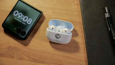 Auriculares Motorola Buds 2 Plus en el estuche de carga con móvil plegable de Motorola al lado