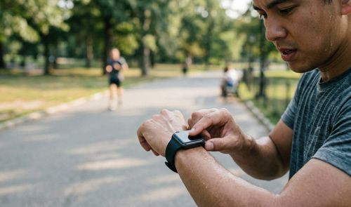 Hombre consultando la frecuencia cardíaca en su Apple Watch tras correr en un parque.