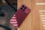 Parte trasera de un teléfono POCO F9 Ultra en color rojo cherry apoyado sobre una mesa de madera con sombras de persiana.