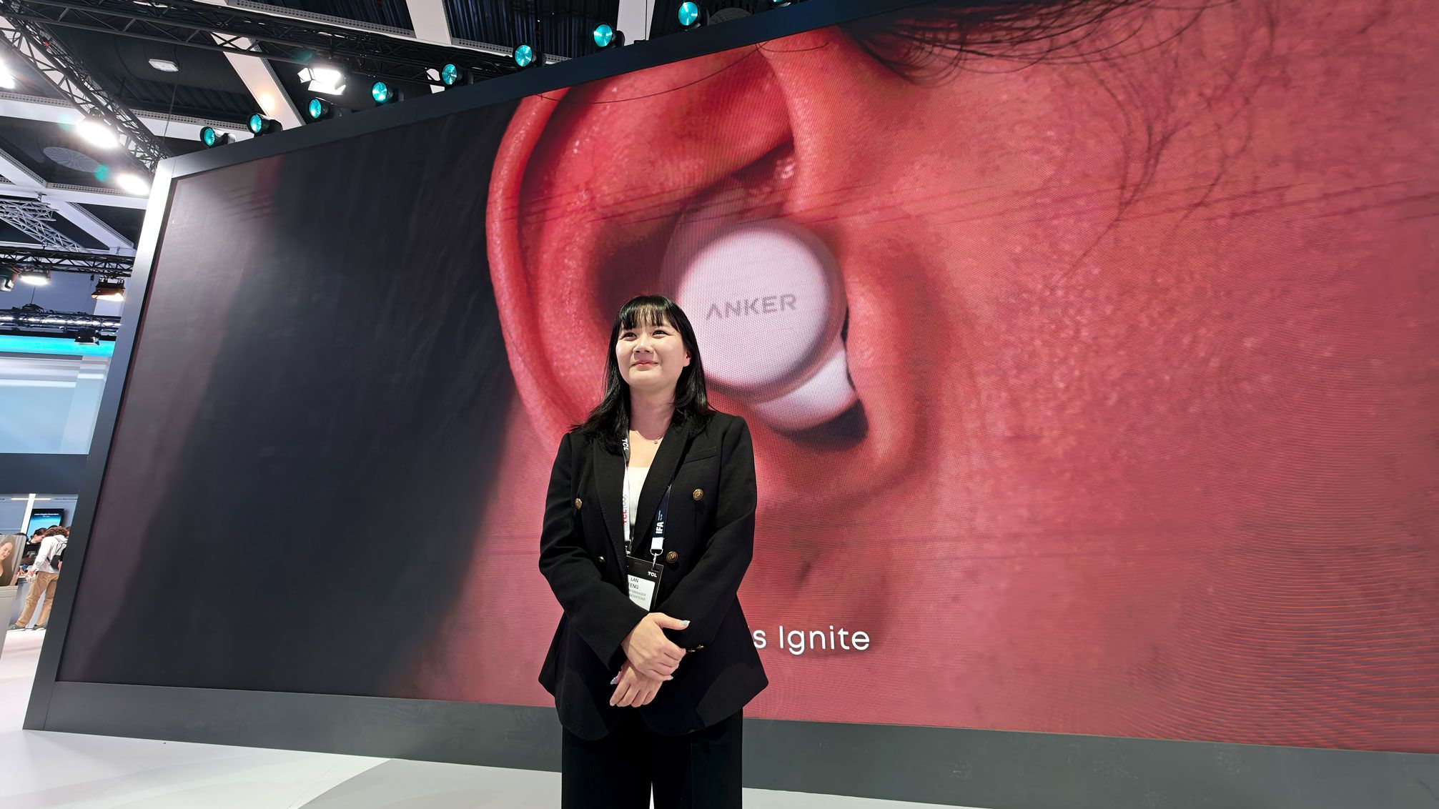 Nora Feng, Anker Spain Country Manager en la feria de la IFA delante de una gran pantalla con el logotipo de Anker
