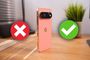 Google Pixel 11 Pro en color rosa sobre una mesa de madera con iconos de verificación y error.